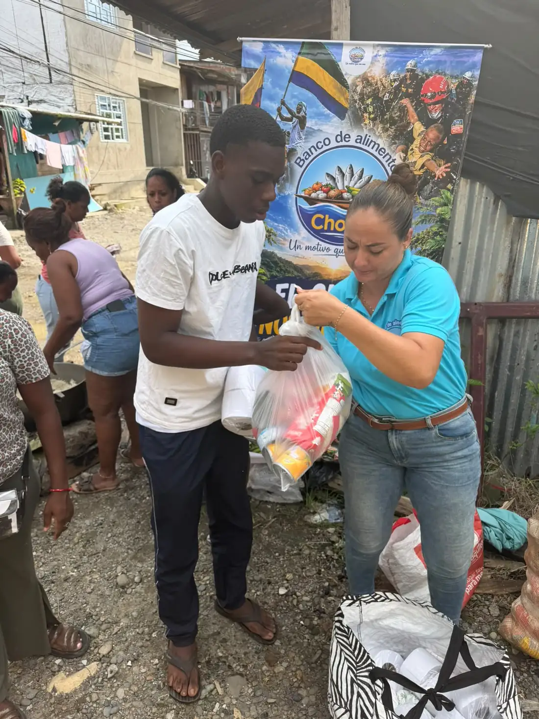 Voluntaria del Banco de Alimentos del Chocó entregando un mercado en mano a un joven en su barrio
