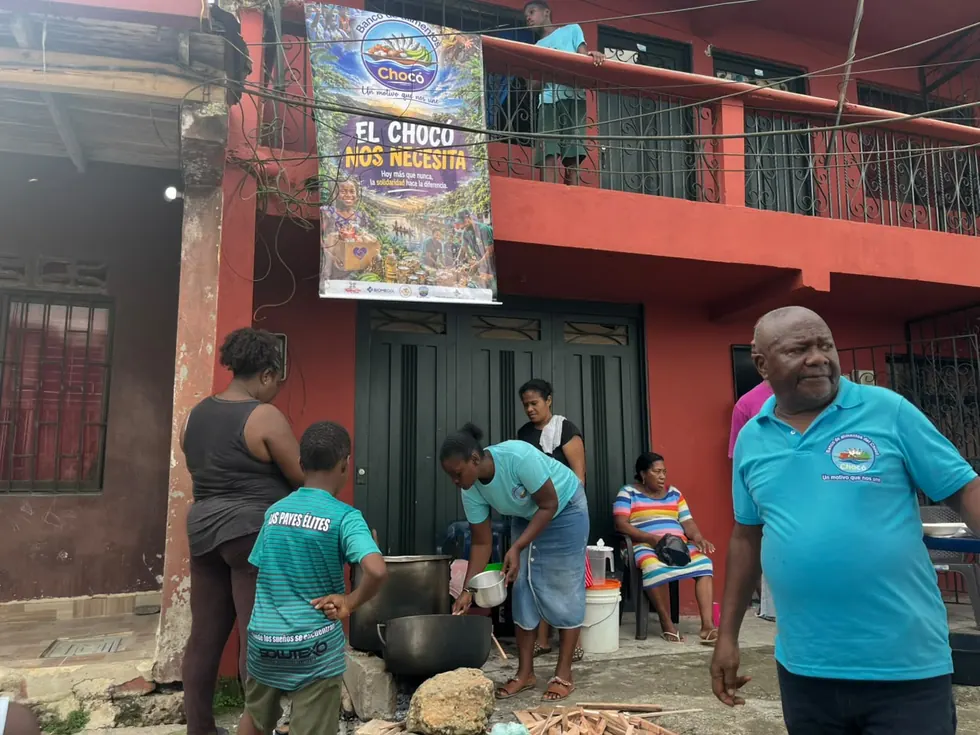 Vecinos del barrio haciendo fila con sus platos alrededor de la olla comunitaria en el Chocó