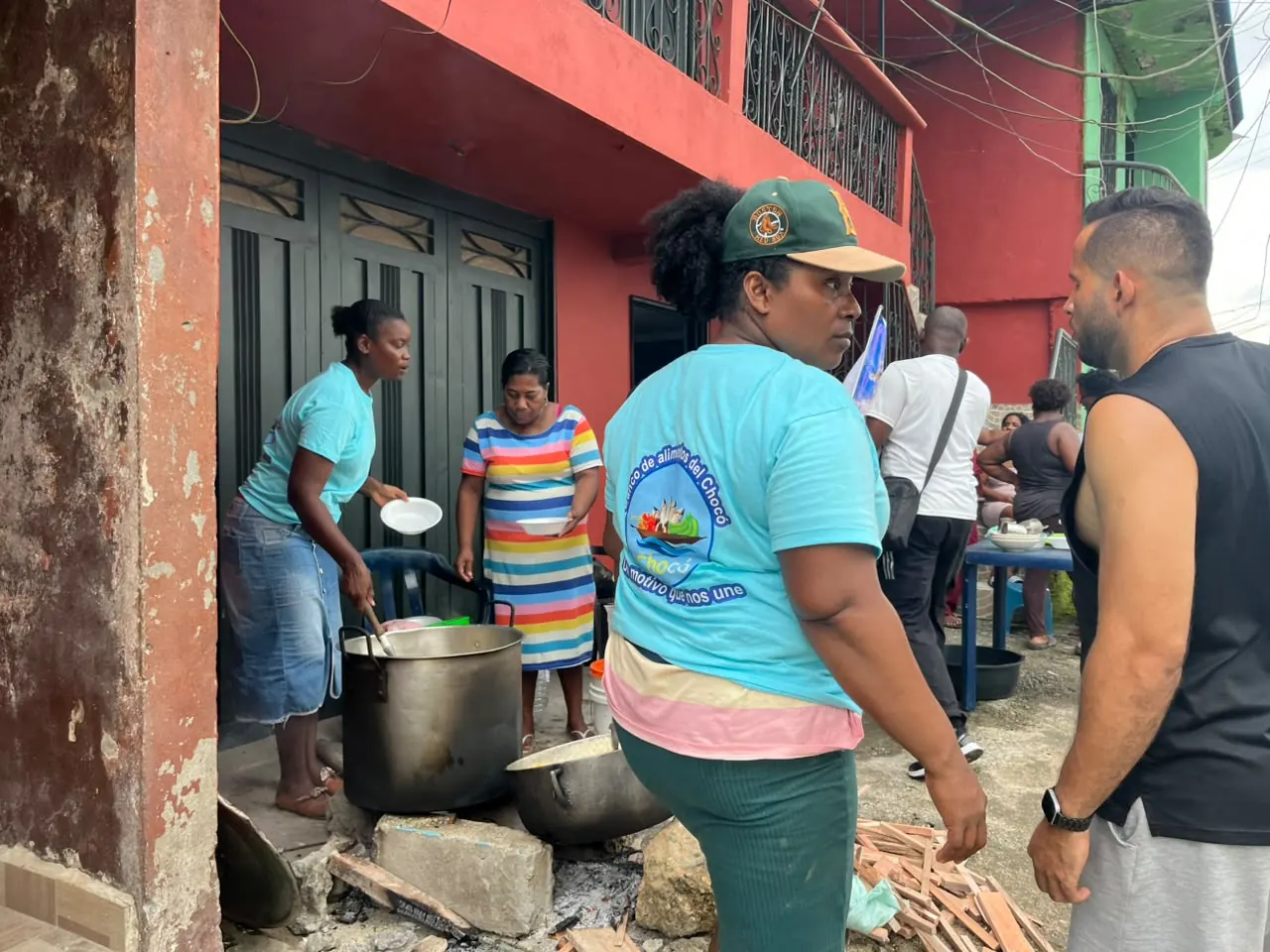 Voluntaria del Banco de Alimentos del Chocó cocinando en una olla grande sobre fogón de leña en la calle