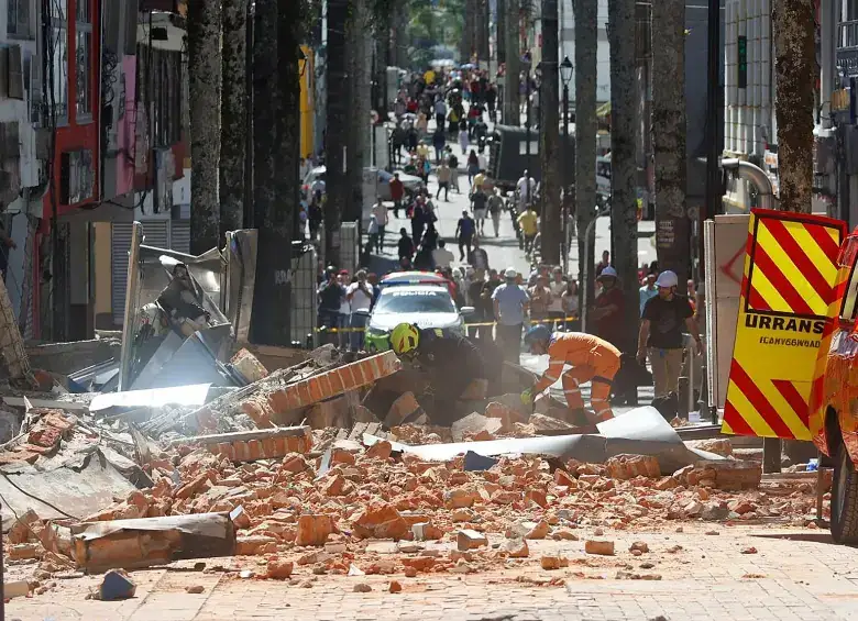 Calle cubierta de escombros con ambulancia y rescatistas trabajando
