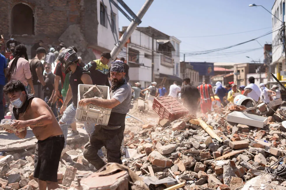 Voluntarios trasladando cajas de ayuda humanitaria entre los escombros tras el sismo