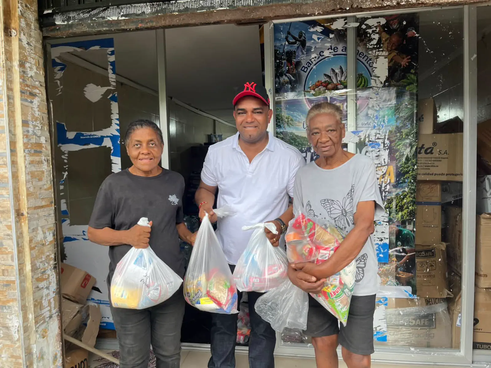 Tres personas del Chocó con las bolsas de mercado que acaban de recibir