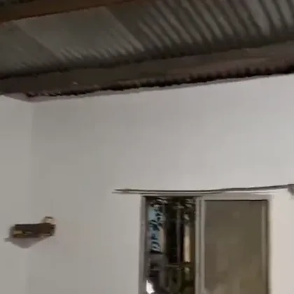 Interior de la casa entregada: paredes blancas y techo de zinc sobre vigas de madera