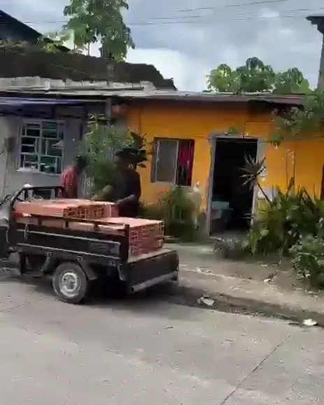 Un motocarro cargado de ladrillos frente a una hilera de casas en una calle de Quibdó